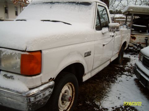 1988 Ford F-150 - A white pickup truck sits in the snow, showing its front quarter panel and side.