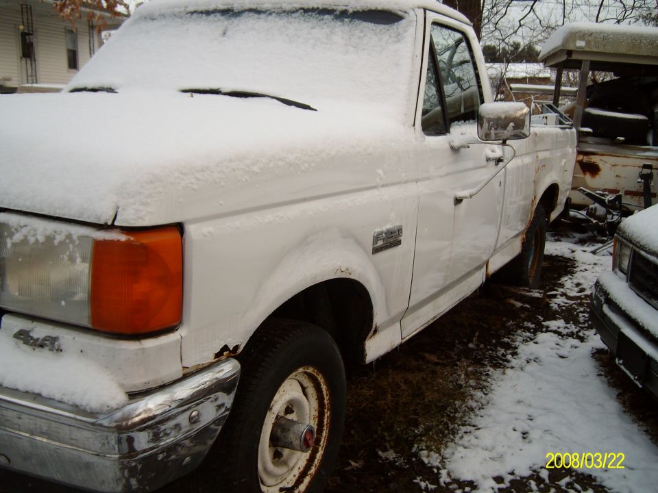 White pickup truck covered in snow, parked next to another vehicle