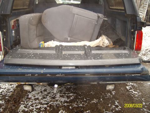 1988 Ford Bronco - Rear view of a blue Ford Bronco with interior parts loaded in the cargo area.