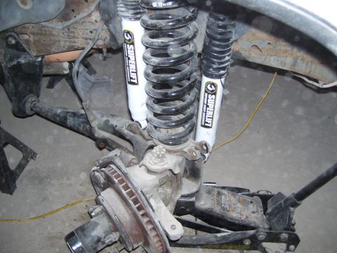 1988 Ford Bronco - The vehicle's front suspension system is disassembled, showing the shock absorbers and brake rotor.