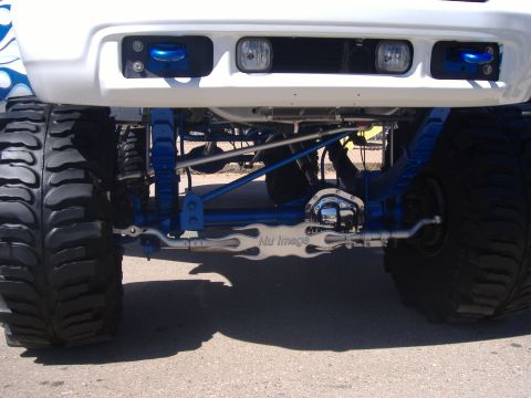 1995 Ford Bronco - Customized truck front end with oversized tires and vibrant blue suspension parts, flame graphics and "Nu Image" branding.