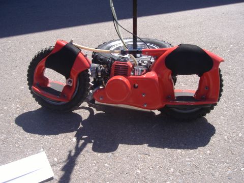 1995 Ford Bronco - This unusual motorized unicycle features a bright red frame, exposed engine, and knobby tires, seen parked on asphalt.