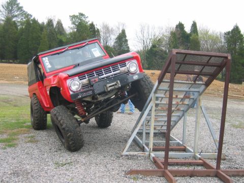 1992 Ford Mustang - A red off-road Bronco is positioned on a metal ramp, its off-road capabilities.