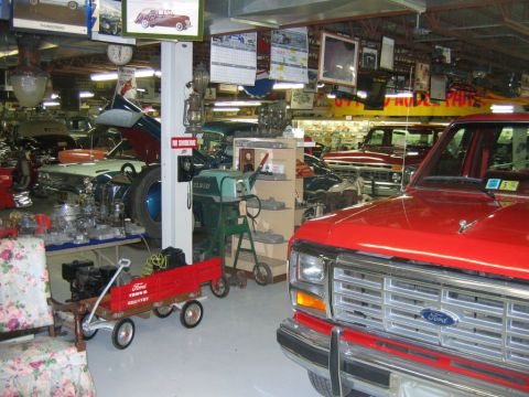 1992 Ford Mustang - A garage filled with classic cars, parts, and automotive memorabilia, including a red Ford truck.