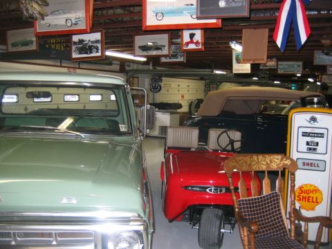 1992 Ford Mustang - A collection of vintage vehicles and memorabilia are displayed in a garage setting.
