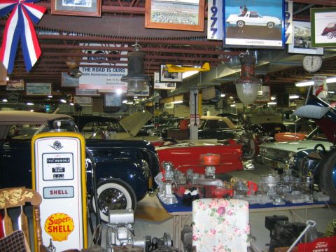 1992 Ford Mustang - A garage filled with classic cars and automotive memorabilia, including a vintage Shell gas pump and various engine parts.