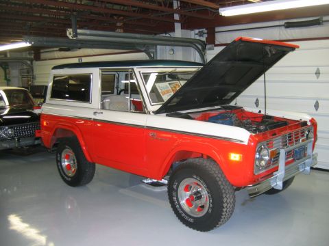 1992 Ford Mustang - This two-tone Ford Bronco is parked inside a garage with its hood up, revealing the engine compartment.