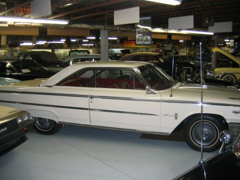 1992 Ford Mustang - A white two-door hardtop car is parked indoors among other vehicles.