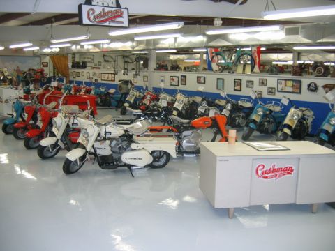 1992 Ford Mustang - A collection of vintage Cushman scooters and motorcycles are displayed in a brightly lit showroom.
