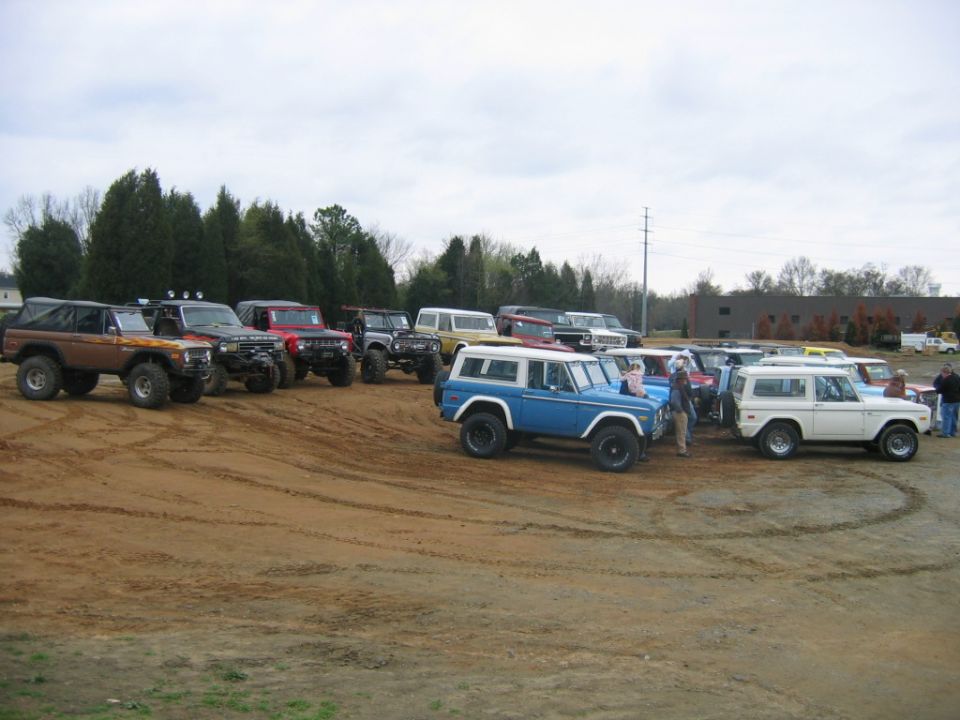 Several Ford Broncos parked on dirt lot, some with tops removed