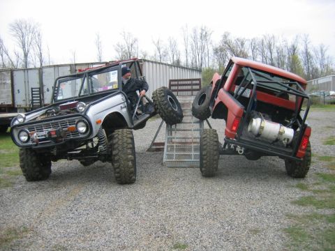 1992 Ford Mustang - Two heavily modified SUVs are positioned on a ramp system in an outdoor lot.