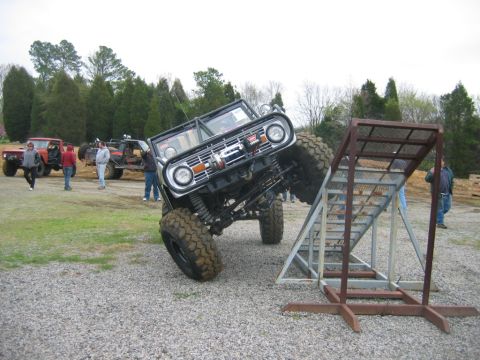 1992 Ford Mustang - A heavily modified Ford Bronco is positioned on a metal obstacle course ramp, with other vehicles and spectators present.