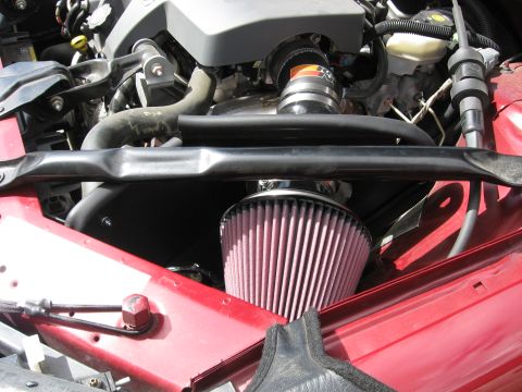 2004 Pontiac Grand Prix - Aftermarket K&N air intake system installed in the engine bay of a red vehicle.