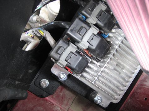 2004 Pontiac Grand Prix - Close-up of an engine control module and its wiring harness, mounted within a vehicle.