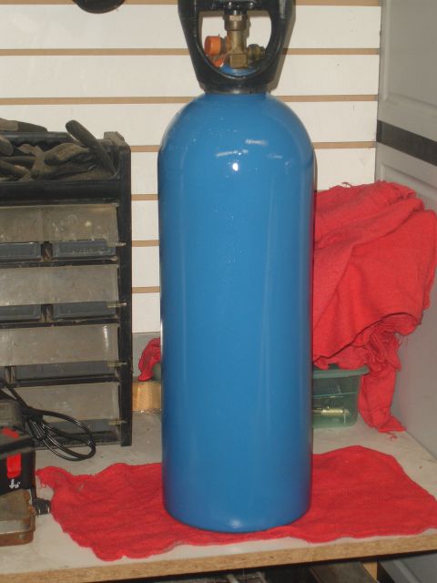 1989 Ford Bronco - A blue compressed gas cylinder with a black regulator is shown on a workbench.