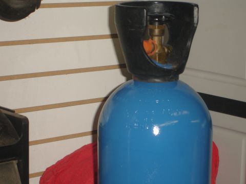 1989 Ford Bronco - A blue gas cylinder with a black protective collar and brass valve is shown up close.