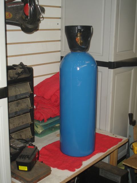 1989 Ford Bronco - A blue gas cylinder sits on a red cloth on a workbench, surrounded by various tools and storage units.