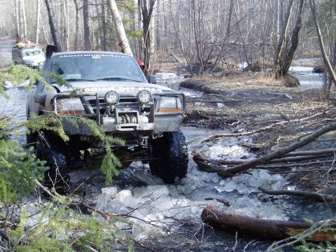 2000 Ford E350 - This modified truck navigates a challenging icy stream in a wooded area.
