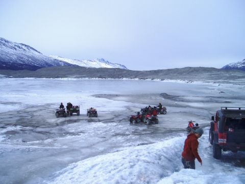 2000 Ford E350 - Several ATVs and a Jeep are parked on a frozen body of water with snow-covered mountains in the distance.