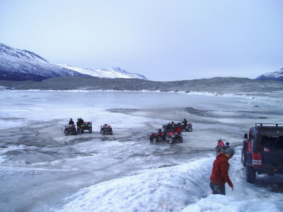 Jeep rear view on icy terrain with ATVs in background