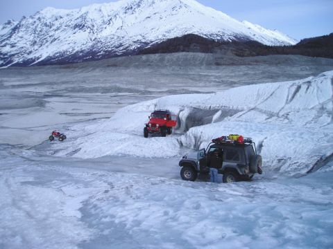 2000 Ford E350 - Off-roading adventure on a glacier with multiple vehicles navigating the icy landscape under a snow-capped mountain.