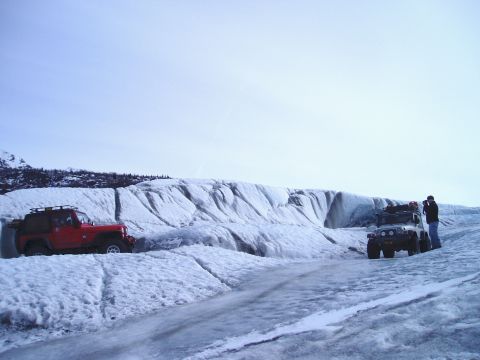 2000 Ford E350 - Two Jeeps are parked on a vast icy landscape, with a person standing by one of them.