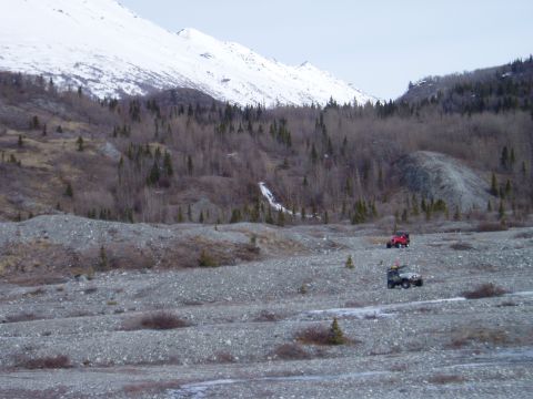 2000 Ford E350 - Off-road vehicles navigate a , rocky landscape under a snow-covered mountain.