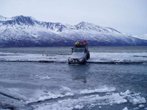 2000 Ford E350 - Jeep Wrangler navigating icy terrain with snow-capped mountains behind it.