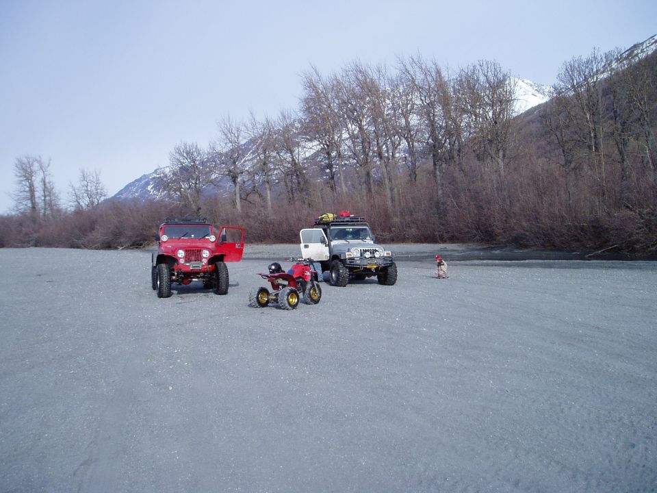 Red Jeep and silver Jeep with an ATV on a plain