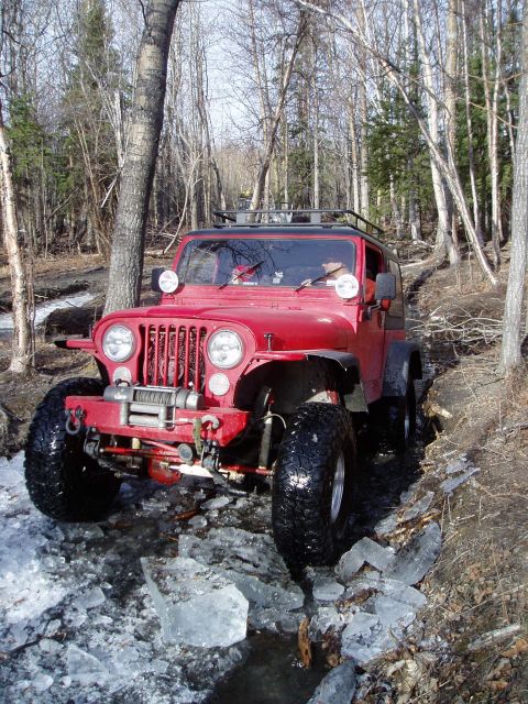 2000 Ford E350 - A red Jeep CJ navigates a challenging path with ice and water.
