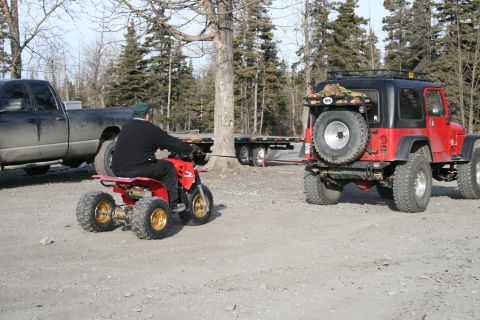 2003 Jeep TJ - A red 2003 Jeep TJ is viewed from the rear, towing a trailer with an ATV attached.