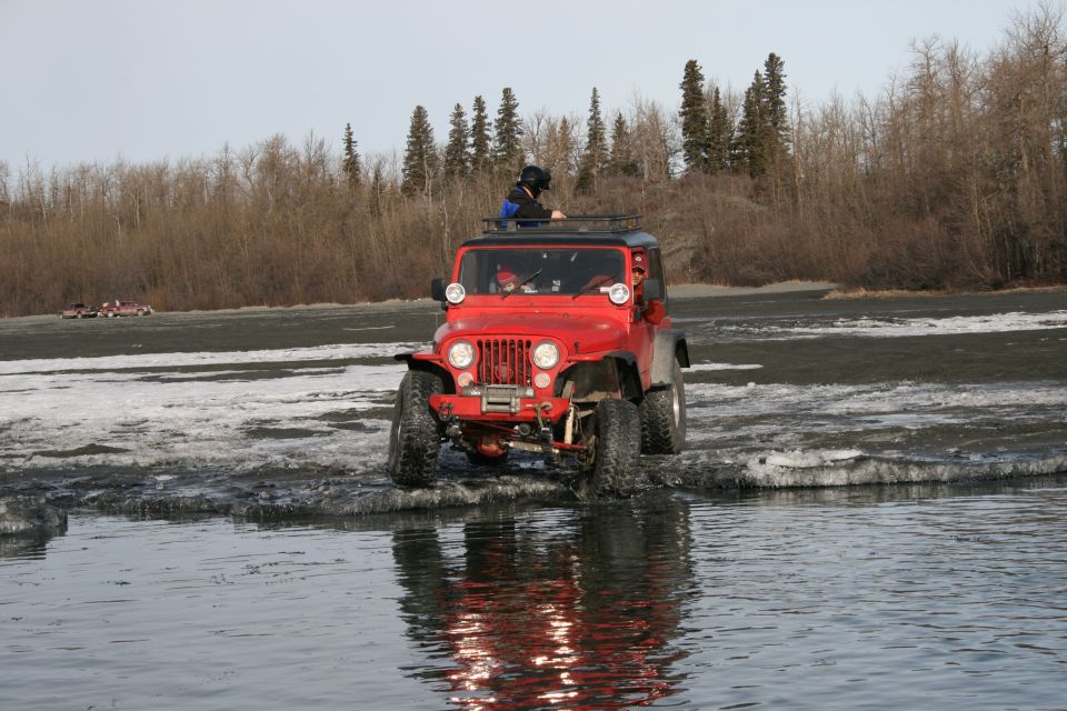 Red Jeep Wrangler driving through shallow water and ice