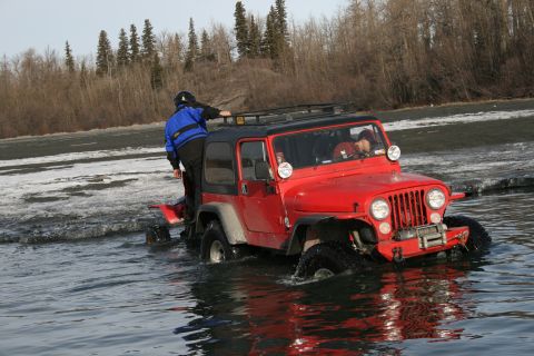 2003 Jeep TJ - A red Jeep Wrangler navigates through icy water near a wooded shoreline.