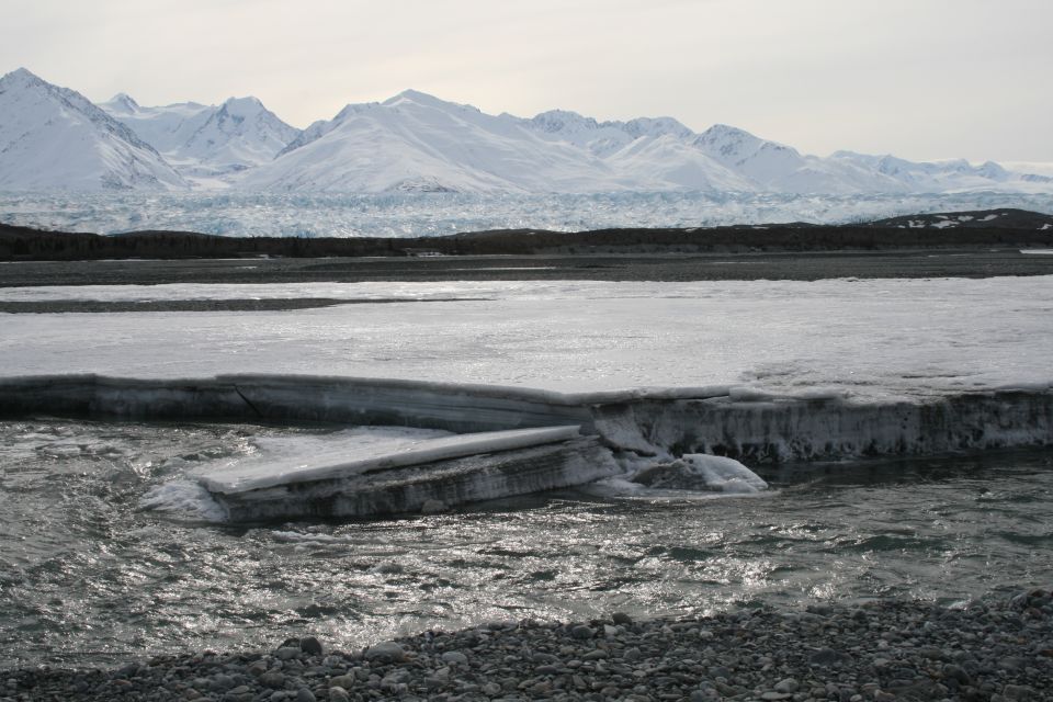 Frozen river with ice floes and snow-capped mountains in background