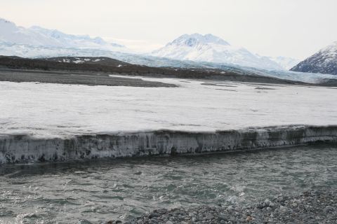 2003 Jeep TJ - A river flows past a large ice formation with mountains in the distance.
