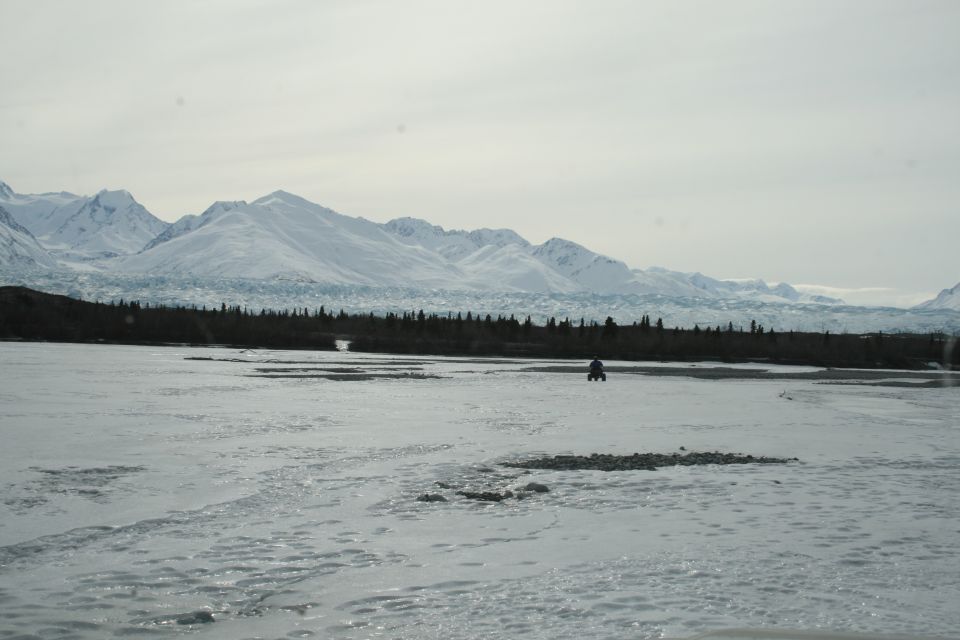 ATV on frozen ground, distant snow-covered mountains and glacier