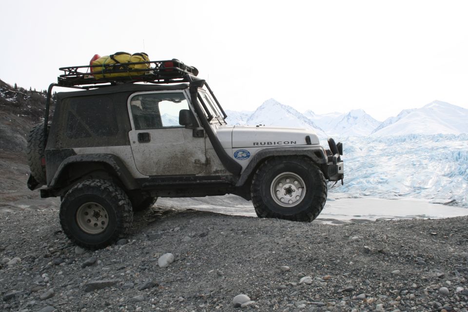 White 2003 Jeep Wrangler Rubicon with snorkel and roof rack parked on gravel with glacier background