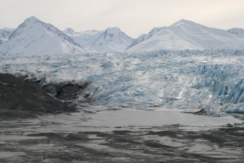 2003 Jeep TJ - A vast glacier stretches towards snow-capped mountains, its blue ice formations glistening under a muted sky.