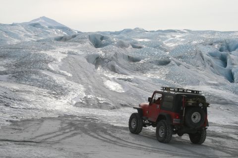 2003 Jeep TJ - A red Jeep navigates a snowy, icy landscape with a large glacier and mountain range visible.