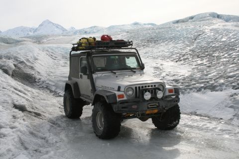 2003 Jeep TJ - A modified Jeep Wrangler navigates a snowy and icy landscape, likely a glacier, with gear on its roof rack.