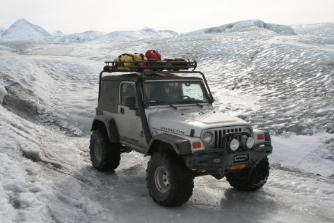 2003 Jeep TJ - A 2003 Jeep TJ navigates a glacial landscape, equipped with a roof rack carrying gear.