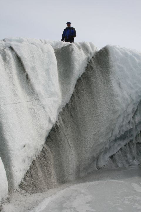 2003 Jeep TJ - A person stands atop a dramatic icy formation on a glacier, highlighting the vastness of the frozen landscape.