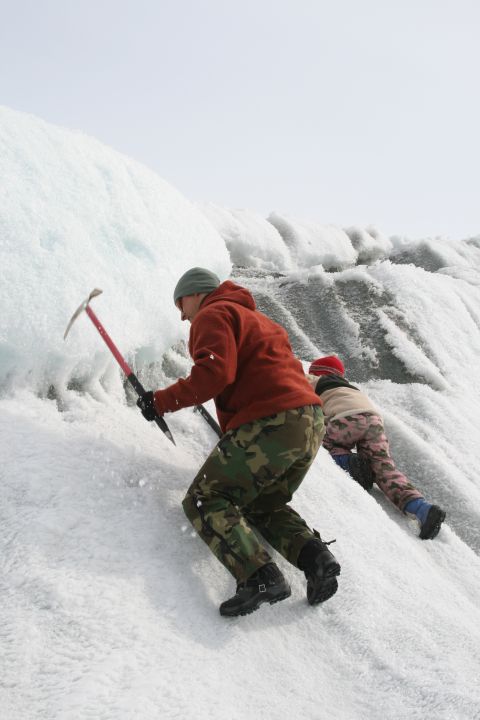 2003 Jeep TJ - Two individuals ascend a steep glacial slope using ice axes for support and traction.