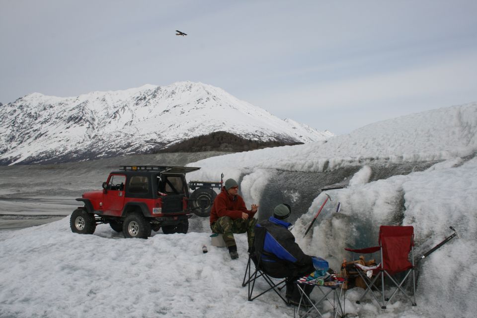 Red 2003 Jeep TJ with roof rack on snow, spare tire carrier visible