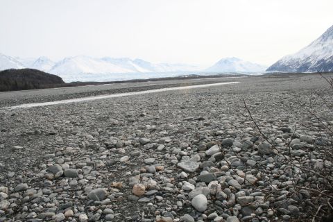 2003 Jeep TJ - A wide, desolate landscape of grey stones stretches towards a distant glacier and snow-covered peaks.