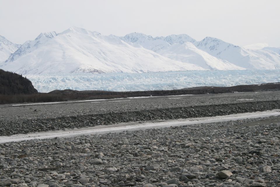 Rocky terrain with a glacier and snow-capped mountains in the background