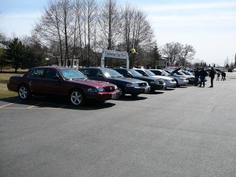 1997 Mercury Grand Marquis - A row of sedans are parked in a lot with a sign that says 'Collector Car Park'.