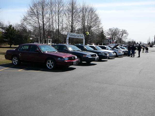 Several sedans parked in a lot, including a maroon one in the foreground