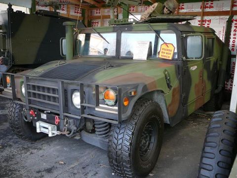 1997 Mercury Grand Marquis - A camouflage Humvee is parked indoors, with another military vehicle partially visible behind it.