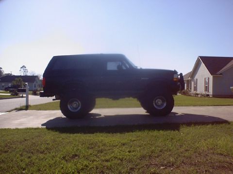 1995 Ford Bronco - This lifted black SUV is seen from the side on a sunny day.